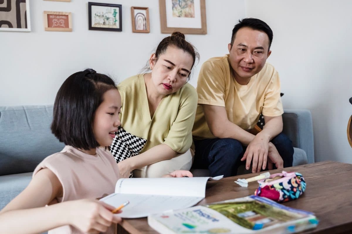 A child studying at home with both parents helping